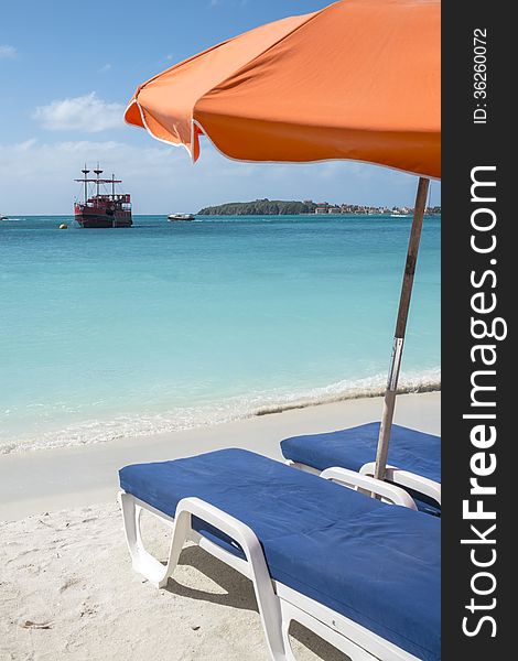 Beach chairs, umbrella and a view of a big ship anchored in the Caribbean sea. Beach chairs, umbrella and a view of a big ship anchored in the Caribbean sea.