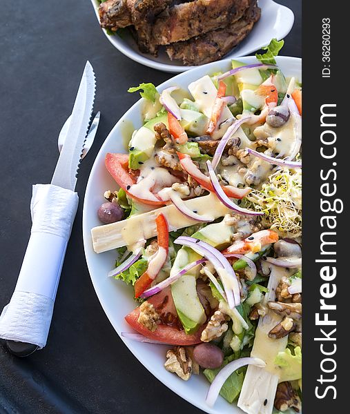 Plateful of salad and a side dish of barbecued ribs. Plateful of salad and a side dish of barbecued ribs.