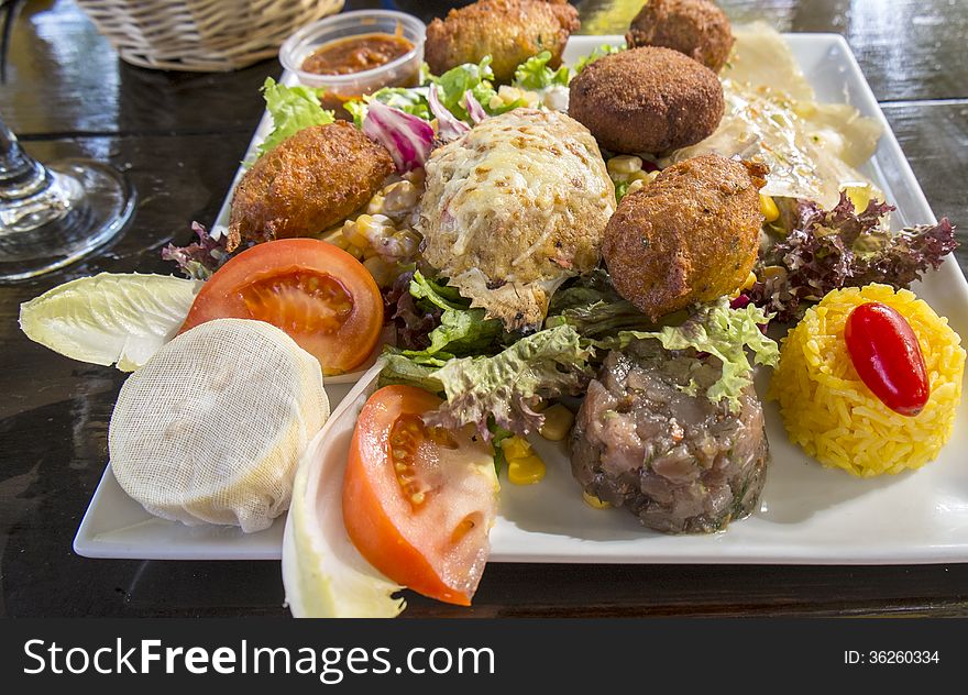 Fried fish fritters, stuffed crab, tuna tartare served with rice and salad. Fried fish fritters, stuffed crab, tuna tartare served with rice and salad.