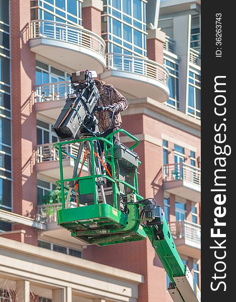 Tv camera man recording event in a city on a lift