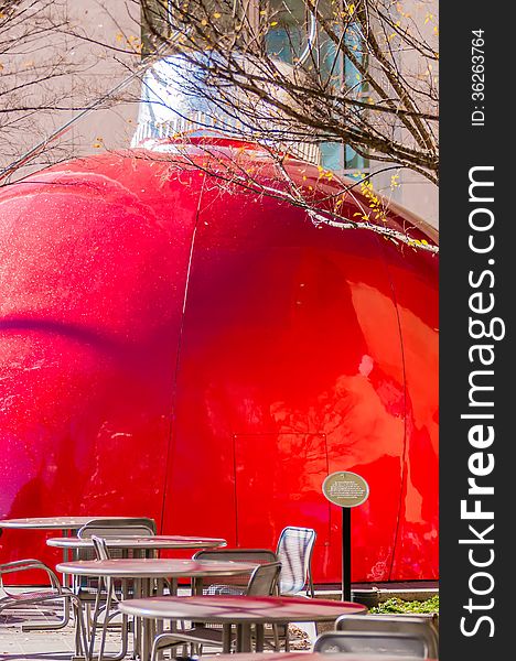Giant red bauble on city plaza behind eating table area