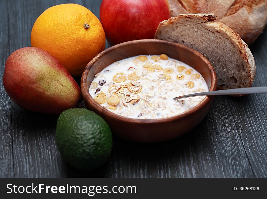 Wooden bowl with muesli and milk near fruits