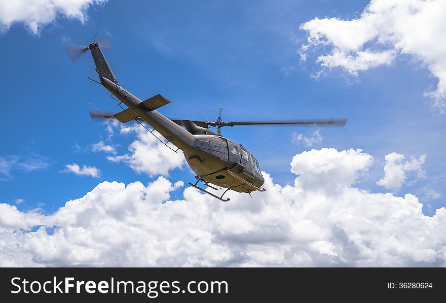 Military helicopter flying through blue sky