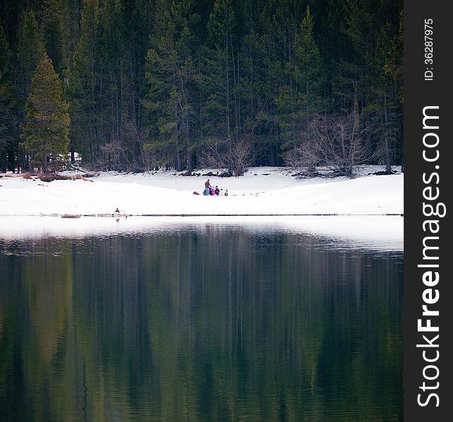 A family enjoying the beautiful scenery at the lakeshore, snow and pine trees at Donner Lake California. A family enjoying the beautiful scenery at the lakeshore, snow and pine trees at Donner Lake California