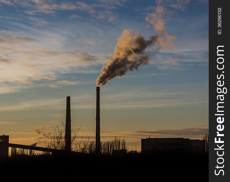 Pipe throws industrial waste gases on the background of the evening sky. Pipe throws industrial waste gases on the background of the evening sky