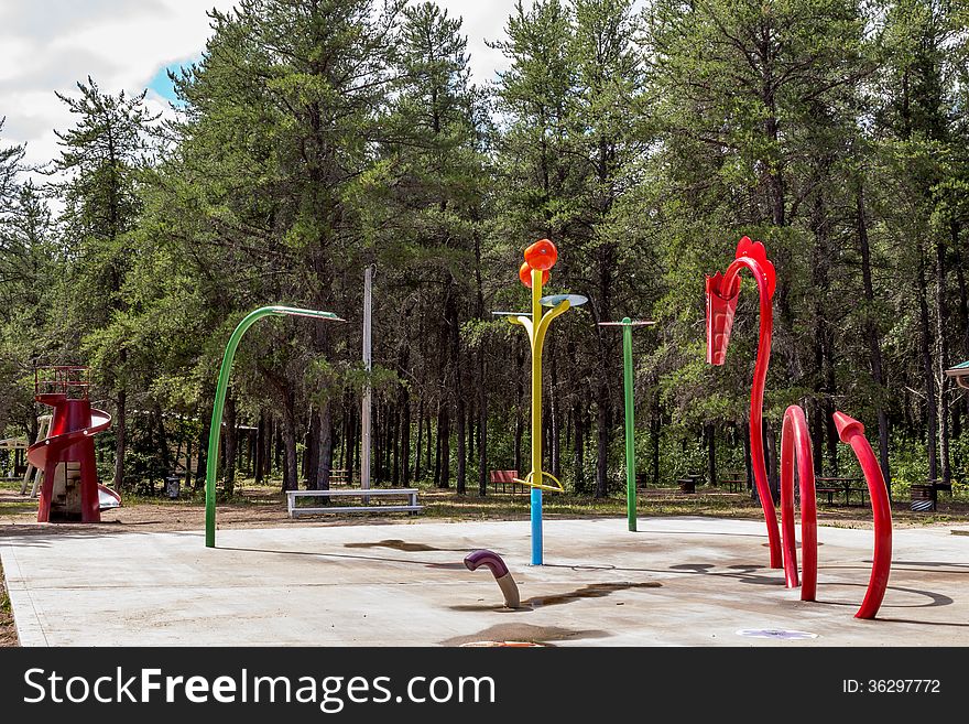 Play structure consisting of a dragon a flower and a slide nestled among the spruce trees at the park. Play structure consisting of a dragon a flower and a slide nestled among the spruce trees at the park