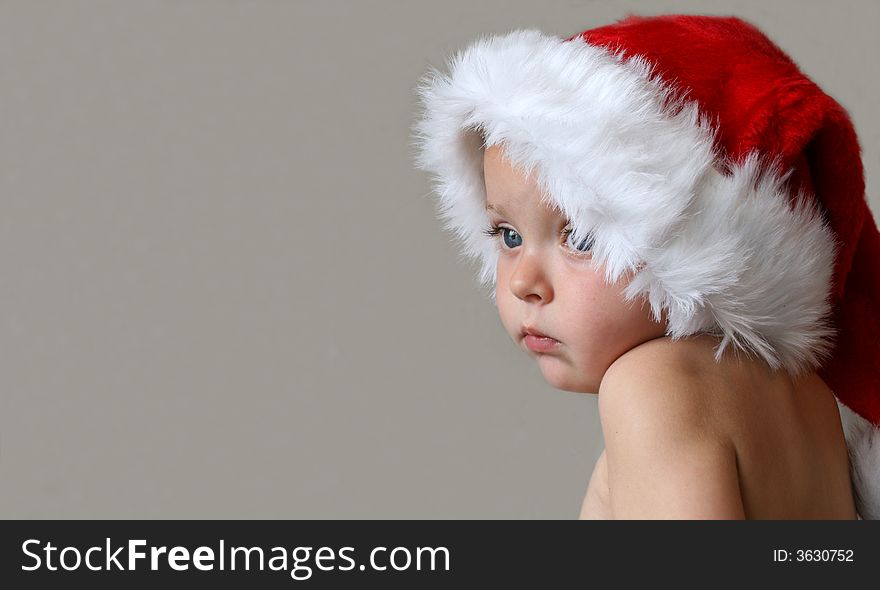 Toddler with a Christmas hat looking into the distance. Toddler with a Christmas hat looking into the distance