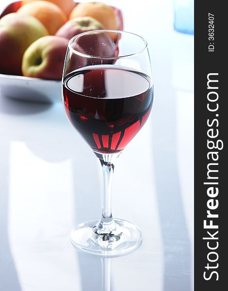 Glass of redwine against some fruits in the background