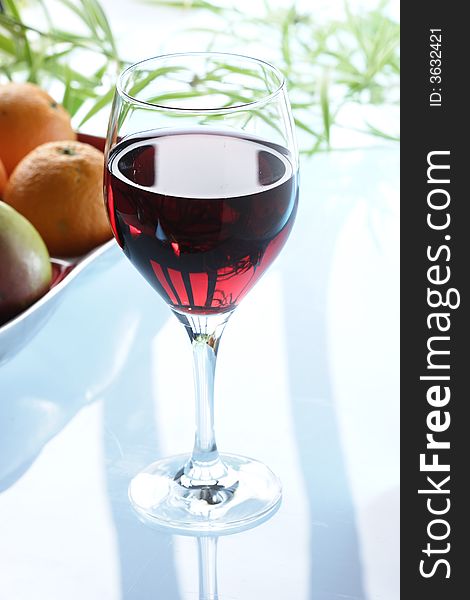 Glass of redwine against some fruits in the background