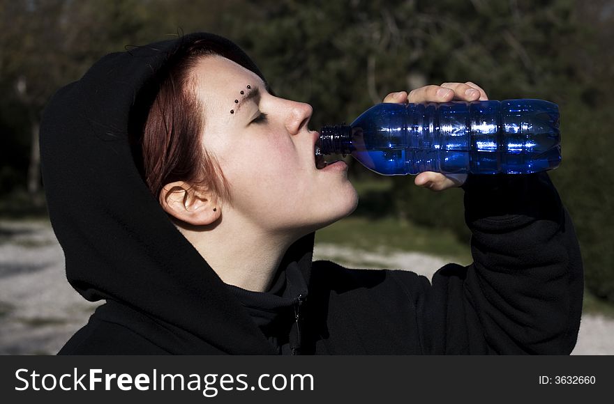 Thirsty girl drinking water on a sunny day.