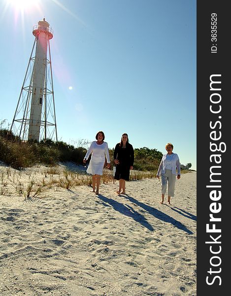 Three women of different generations walking along beach near lighthouse in Boca Grande Florida . Three women of different generations walking along beach near lighthouse in Boca Grande Florida