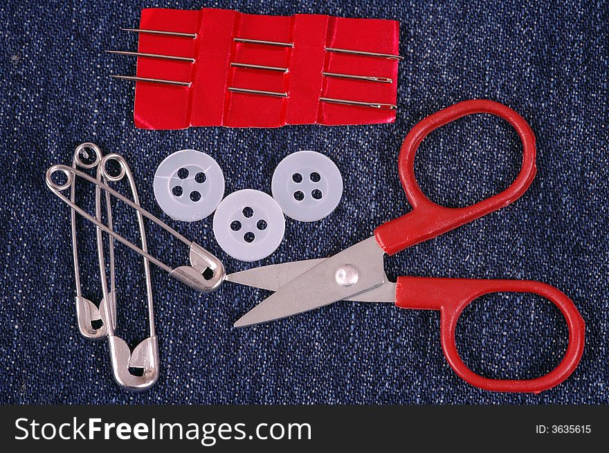 A small sewing kit on denim material.  A macro image taken in a studio. A small sewing kit on denim material.  A macro image taken in a studio.