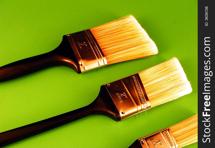 Three paintbrushes against a green background. Three paintbrushes against a green background.