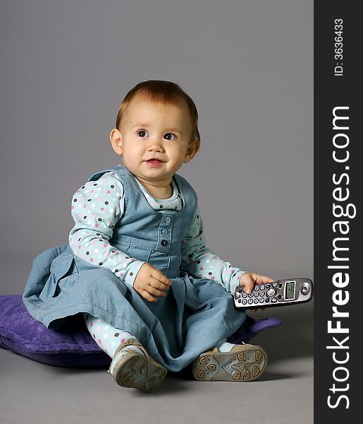 The child calling by phone on a grey background with a smile