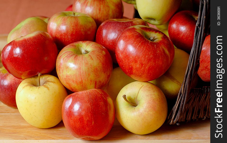 Basketfull of fresh organic apples overflowing onto a table. Basketfull of fresh organic apples overflowing onto a table