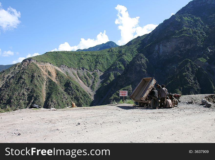 People fixing a tractor in Tibet, and Tibetan mountainous nature in the background