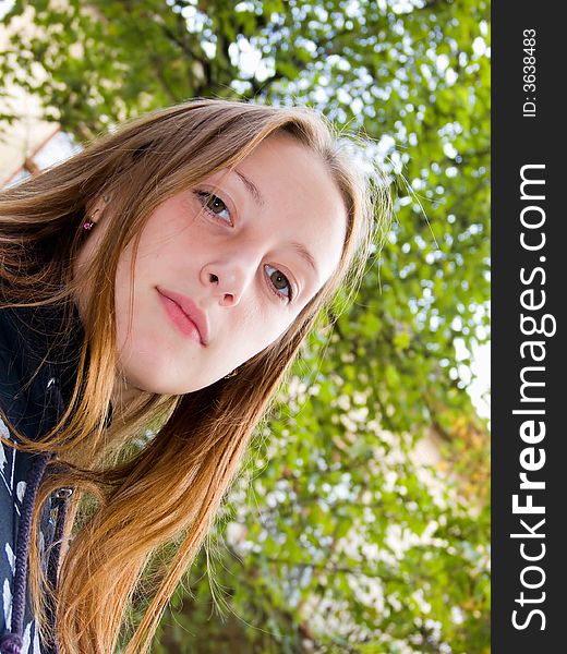 The lovely girl stands under a green tree. The lovely girl stands under a green tree