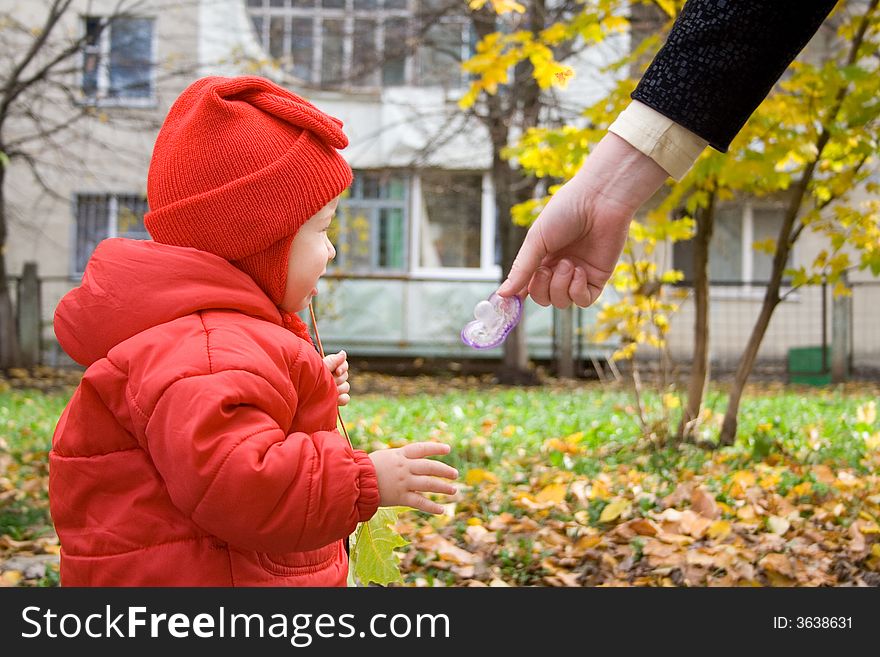 Baby in red shirt and mother hand with dummy. Baby in red shirt and mother hand with dummy