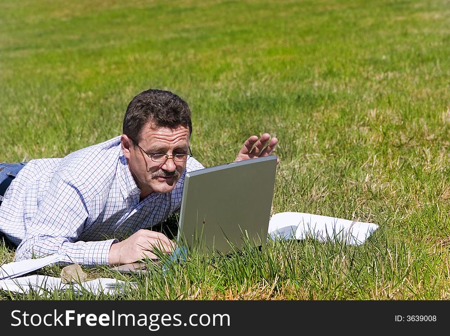 Businessman laying on the grass with his laptop and smiling :-). Businessman laying on the grass with his laptop and smiling :-)