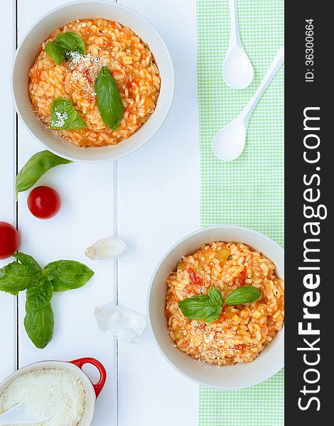 Overhead view of two cooked bowls of Italian pasta in savoury sauce with fresh cherry tomatoes and basil leaves as a garnish. Overhead view of two cooked bowls of Italian pasta in savoury sauce with fresh cherry tomatoes and basil leaves as a garnish