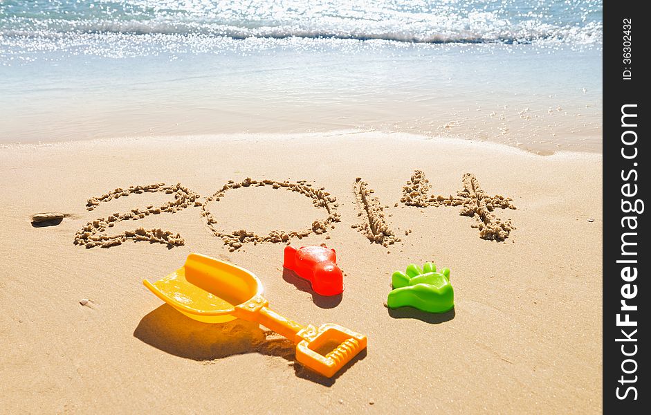 Digits 2014 and toys on the sand seashore - concept of new year and vacation. Digits 2014 and toys on the sand seashore - concept of new year and vacation