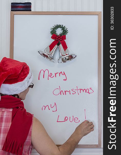 Lady in santa hat writing on white board