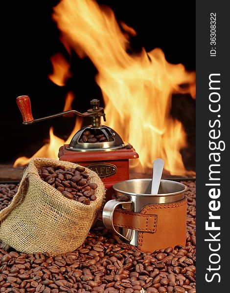 Coffee Mug and, jute sack with coffee beans and grinder on a background of fire. Coffee Mug and, jute sack with coffee beans and grinder on a background of fire