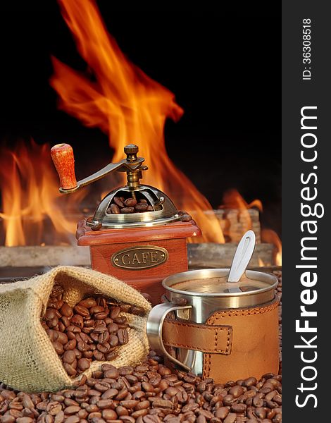 Coffee Mug and, jute sack with coffee beans and grinder on a background of fire. Coffee Mug and, jute sack with coffee beans and grinder on a background of fire