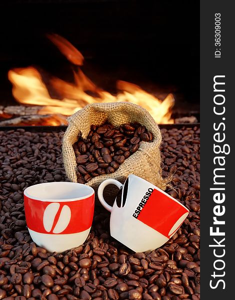 Two ceramic cups and a jute sack with coffee beans on a background of fire. Two ceramic cups and a jute sack with coffee beans on a background of fire