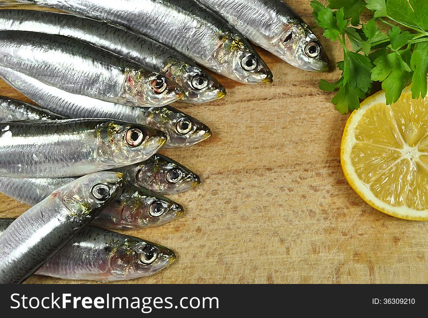 Anchovies, the sea fish with fresh parsley and lemon on a wooden background