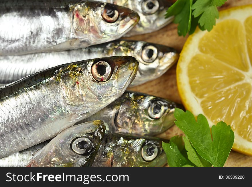 Anchovies, the sea fish with fresh parsley and lemon on a wooden and background