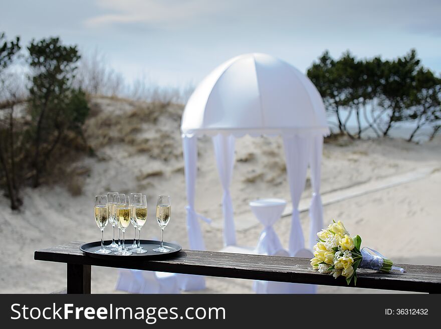 Champagne and bouquet of yellow tulips in front of outdoor wedding ceremony at beach. Champagne and bouquet of yellow tulips in front of outdoor wedding ceremony at beach