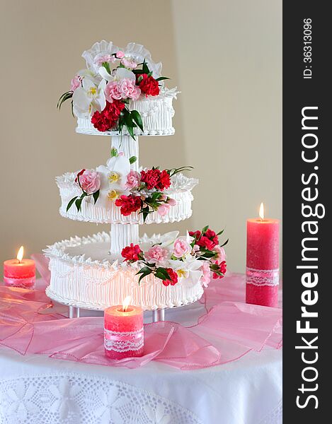 Luxurious wedding cake with pink details and candles around