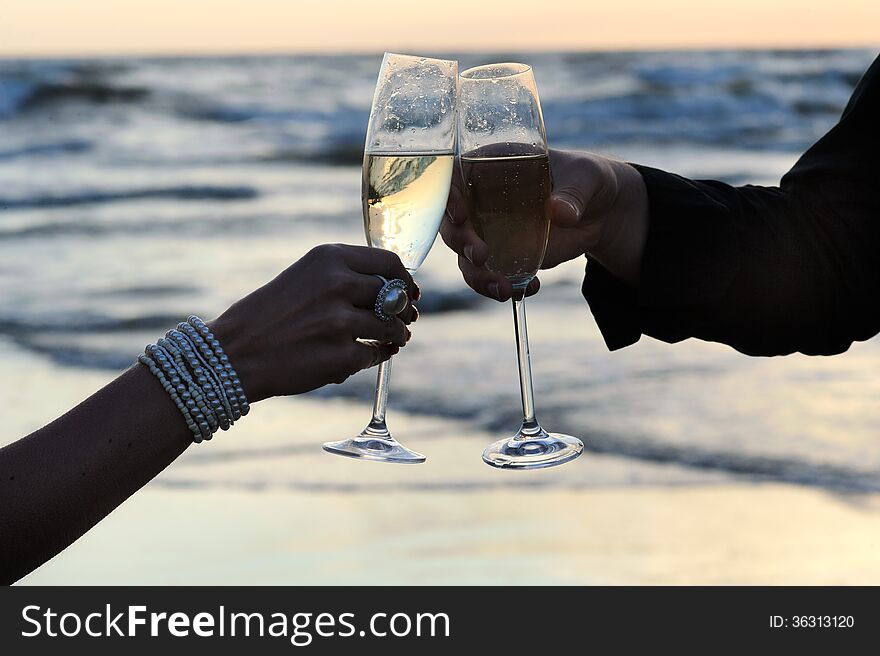 Womens and mens hands holding glasses of champagne at beach. Womens and mens hands holding glasses of champagne at beach