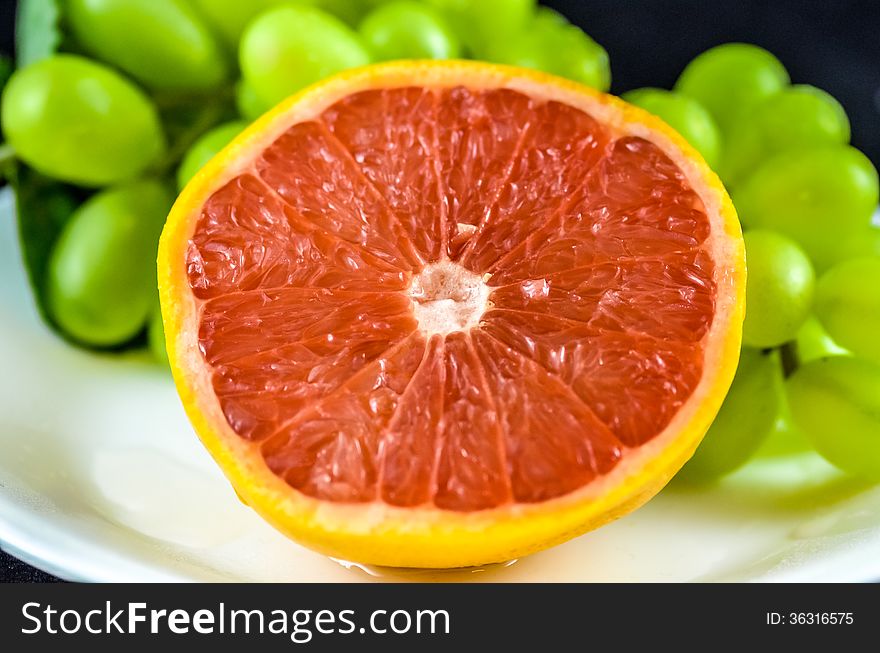 Freshly cut grapefruit with green grapes in the background.