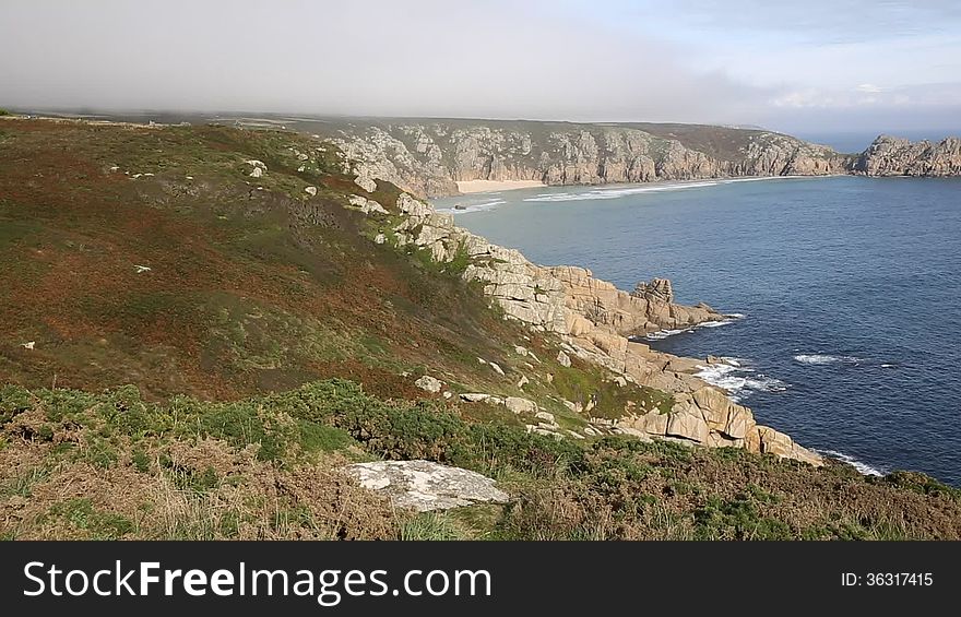 Coast of Cornwall England in autumn with mist and blue sky near the Minack Theatre and Porthcurno