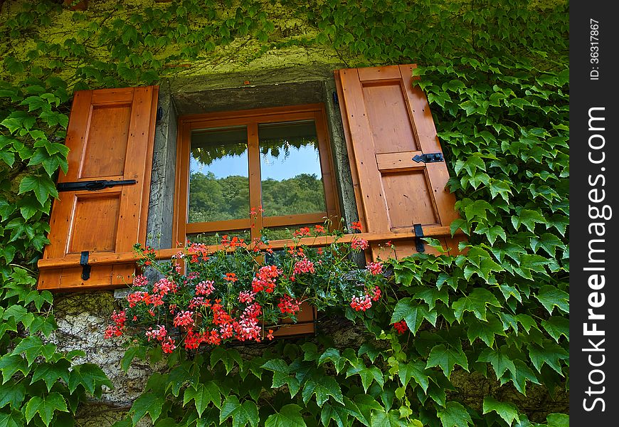 Typical Italian creative window with wooden shutters and beautiful colorful flowers