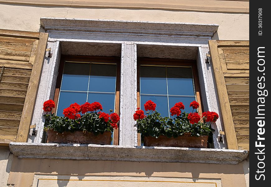 Typical Italian creative window with wooden shutters and beautiful colorful flowers