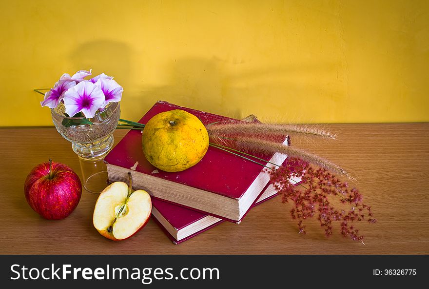 Antique book with wild flower and fruit on table with yellow wall. Antique book with wild flower and fruit on table with yellow wall