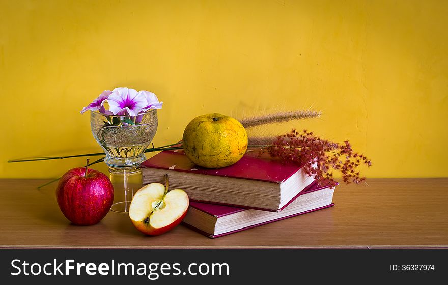 Antique book with flower and fruit on table with yellow background