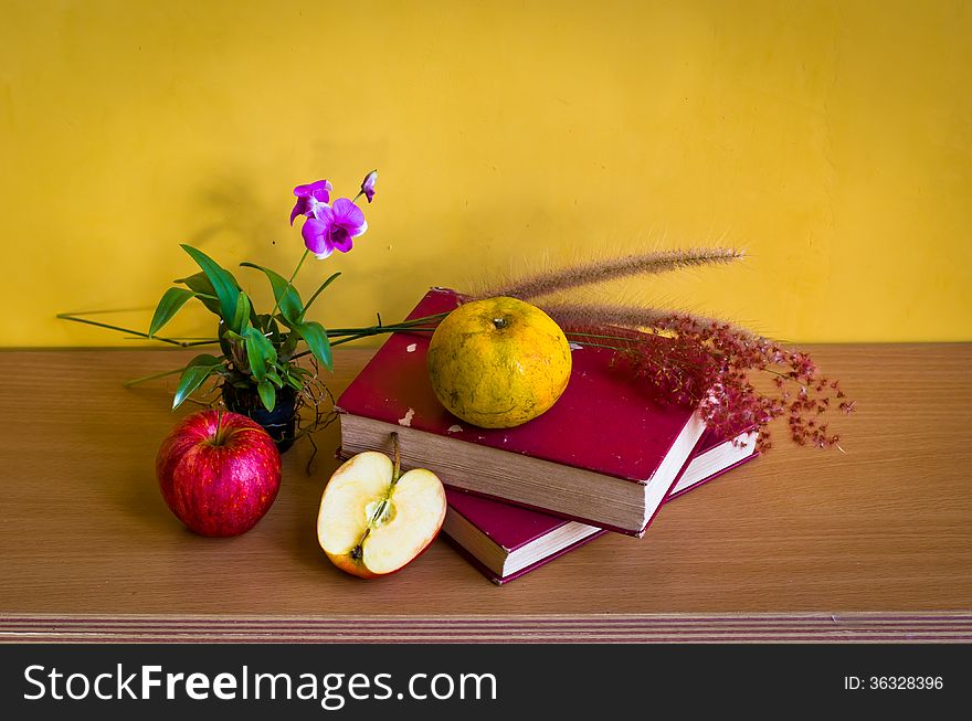 Antique book with flower and fruit on table with yellow background