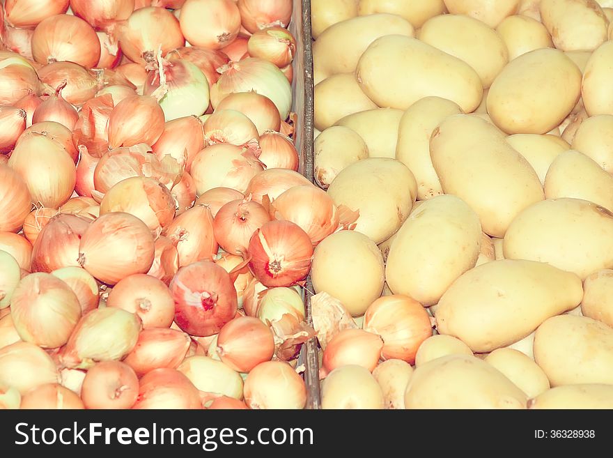 Horizontal background of golden onions and potatoes, vintage style.