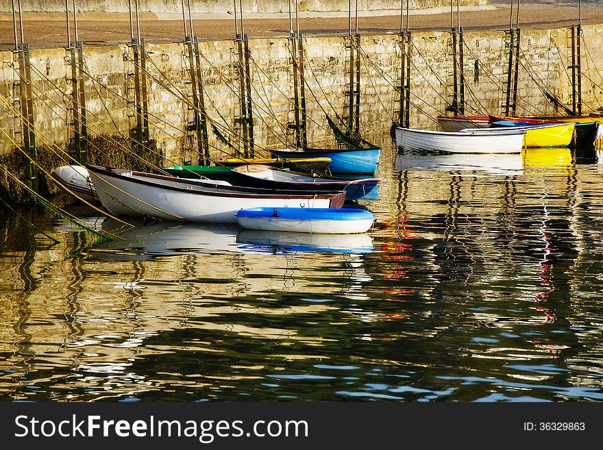 Row-boats sit idle waiting to ferry their owners to larger boats in the harbour. Row-boats sit idle waiting to ferry their owners to larger boats in the harbour.