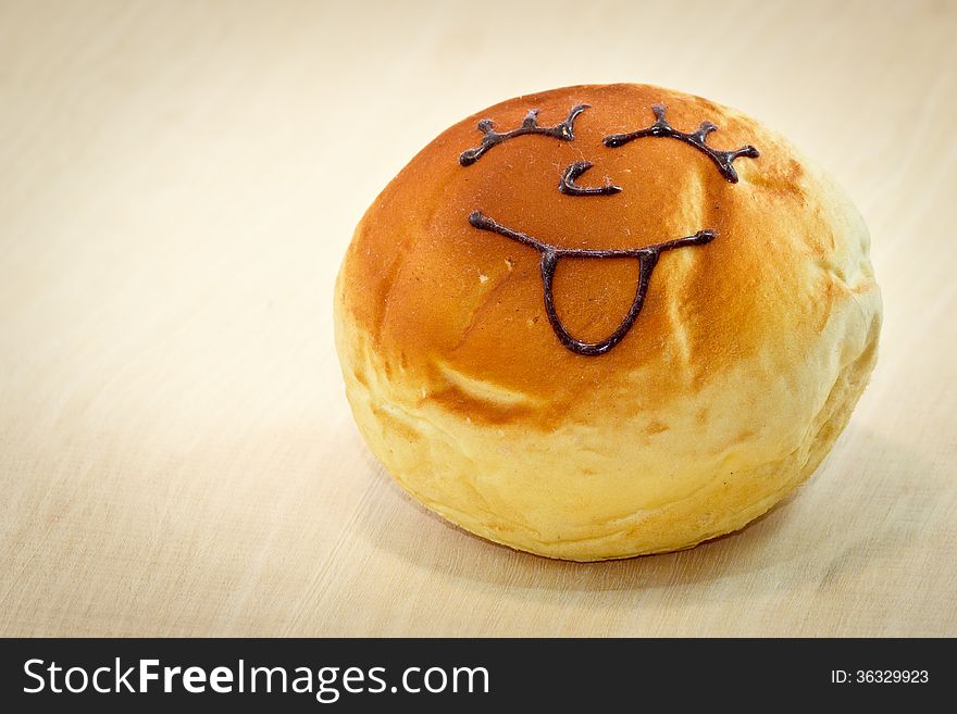 Bread with smile chocolate on wood background
