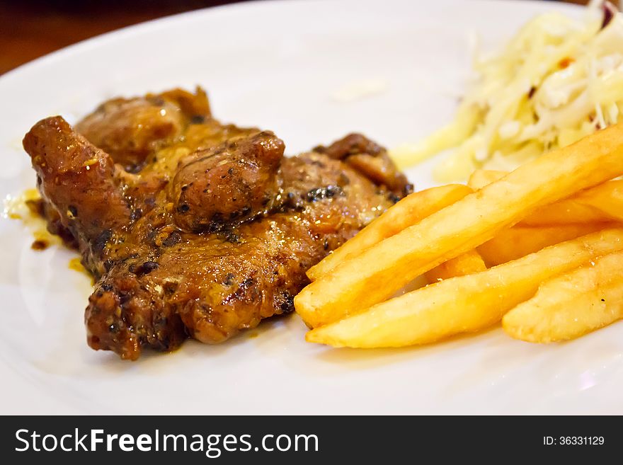 Grilled steaks, fried potatoes and vegetable salad