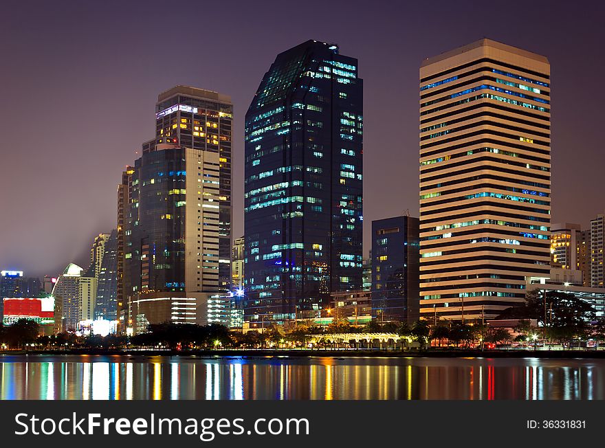 Night cityscape, office buildings and apartments in Thailand at dusk. View from public park.