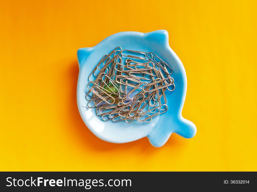 Paper clip on blue plate and orange background