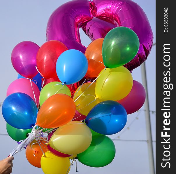 Large group of brightly coloured balloons against a blue sky