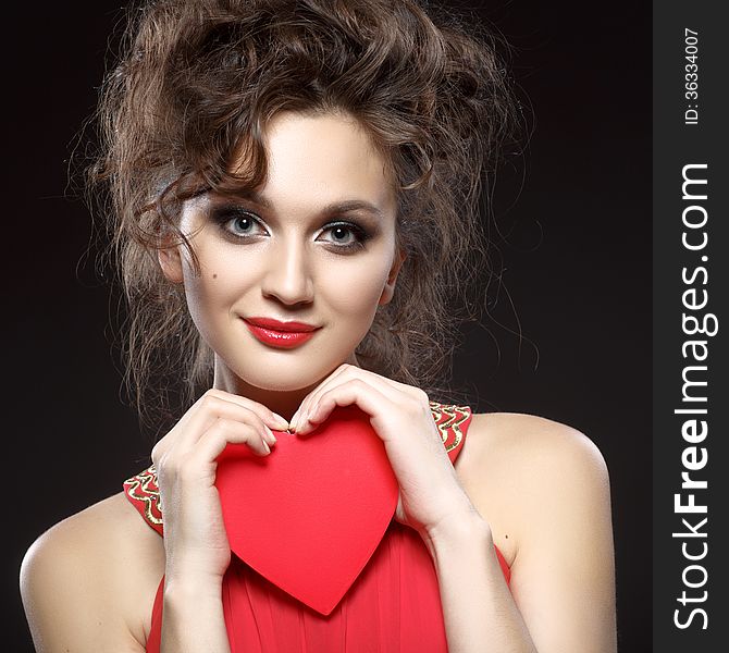 Girl in red dress keeps the heart. Concept of Valentine's Day. Dark background. Girl in red dress keeps the heart. Concept of Valentine's Day. Dark background.