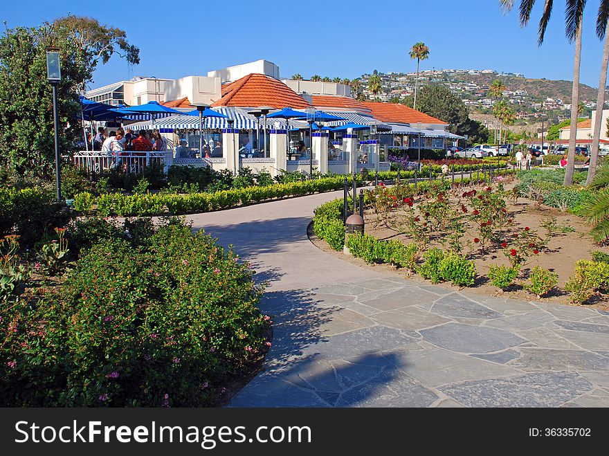 The image shows part of the Heisler Park walkway, Laguna Beach, California. Situated on a bluff, Heisler Park is noted for its spectacular landscaped environment and views of downtown Laguna and picturesque, rocky shoreline. The white building with red tiles is the popular Las Brisas Restaurant which was the former Victor Hugo Inn. The image shows part of the Heisler Park walkway, Laguna Beach, California. Situated on a bluff, Heisler Park is noted for its spectacular landscaped environment and views of downtown Laguna and picturesque, rocky shoreline. The white building with red tiles is the popular Las Brisas Restaurant which was the former Victor Hugo Inn.